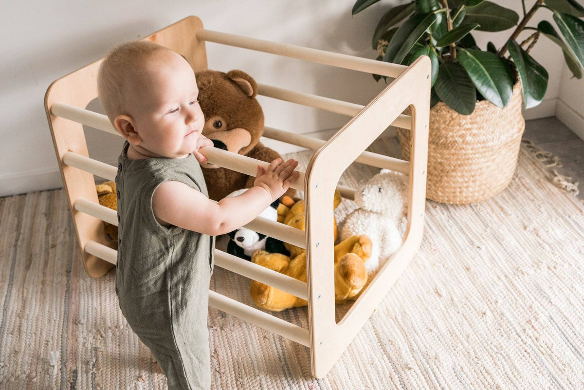 Toddler pulling up on a wooden climbing frame at home